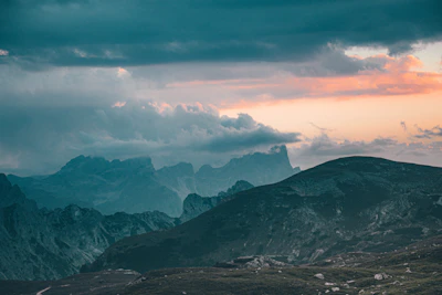 A serene landscape of rolling hills under a dramatic cloudy sky.