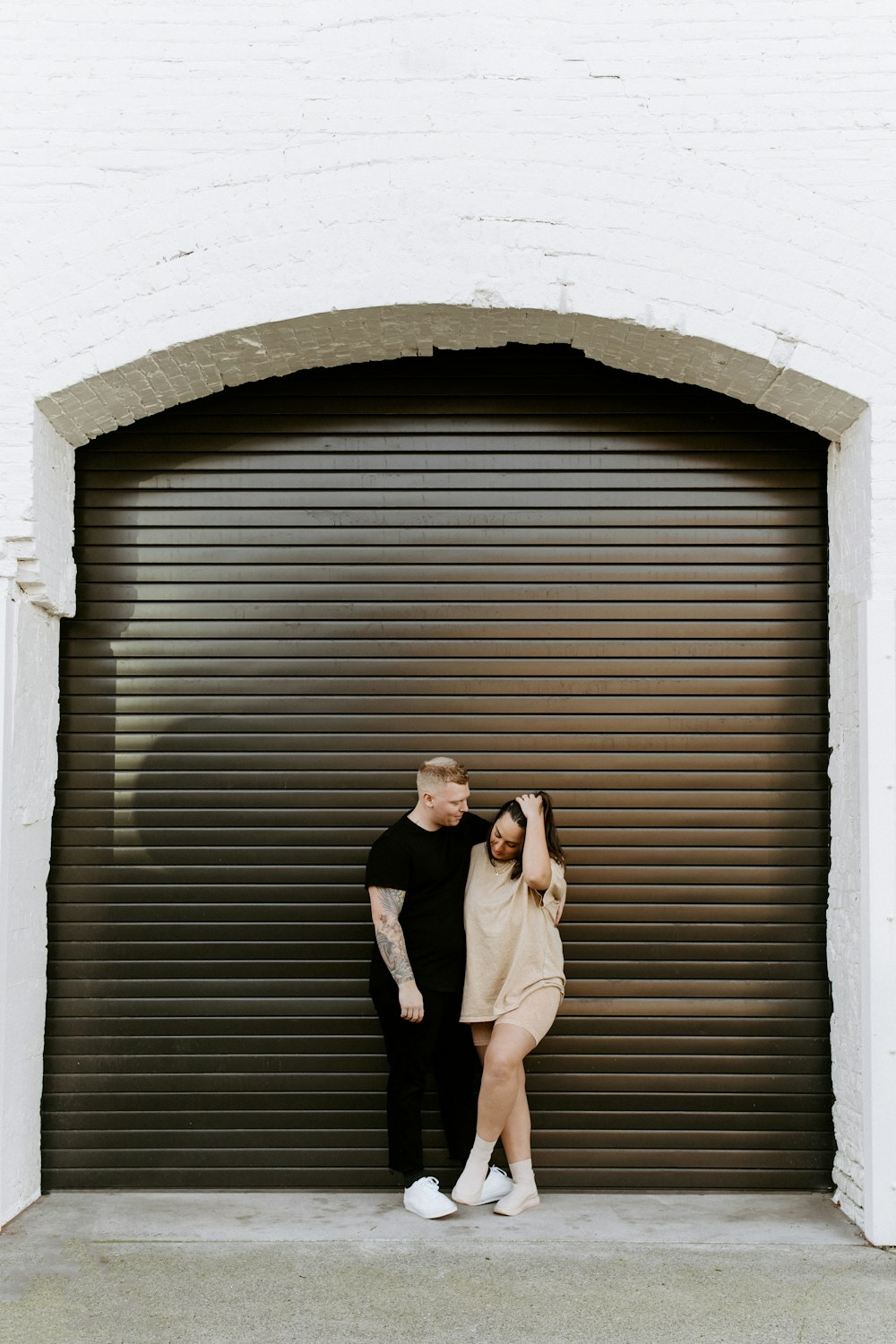 woman in black blazer and white dress standing beside brown wooden door