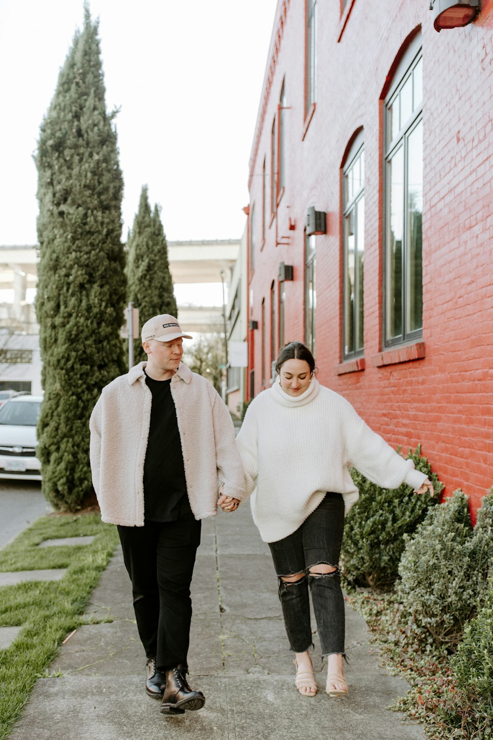 man in white sweater and black pants holding hands with man in black suit jacket