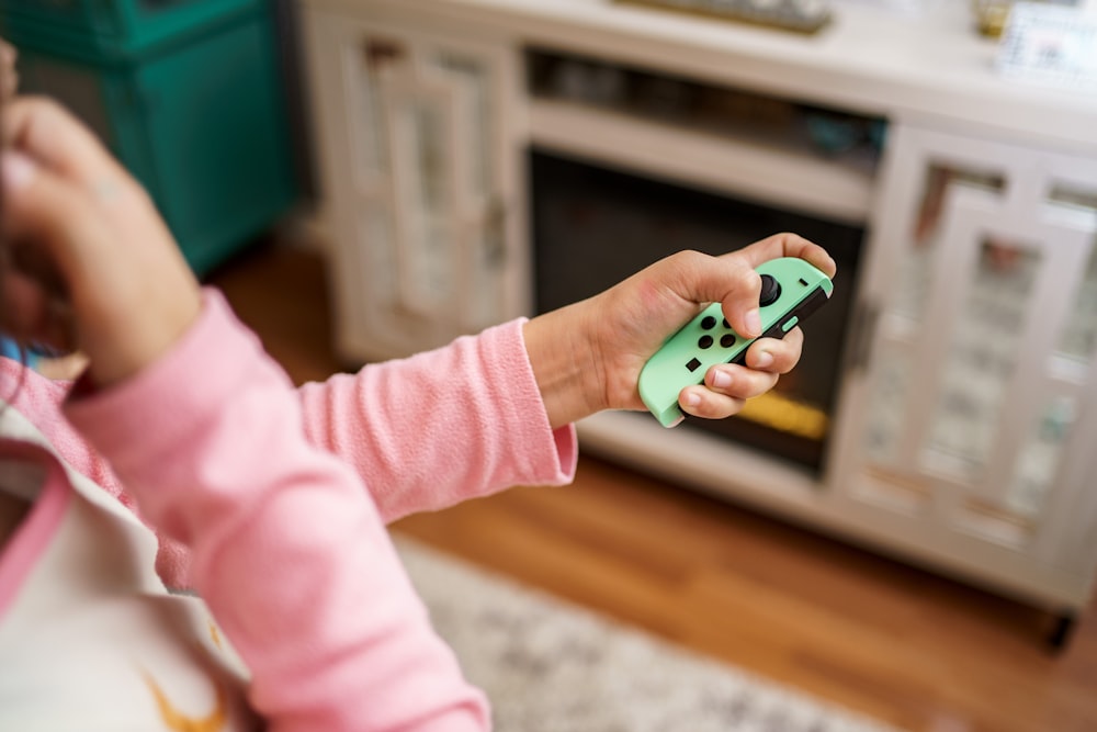 child in pink long sleeve shirt holding green and white plastic toy