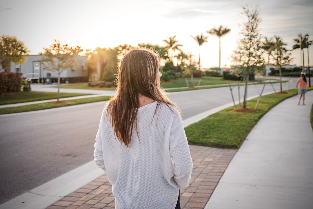woman in white sweater standing on sidewalk during daytime