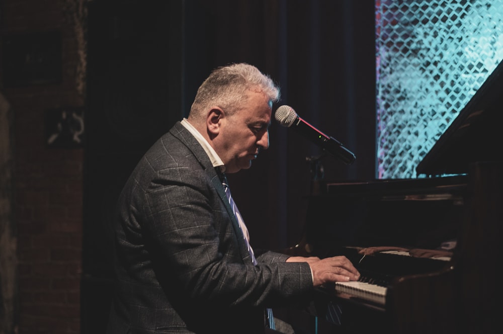 man in black suit jacket playing piano