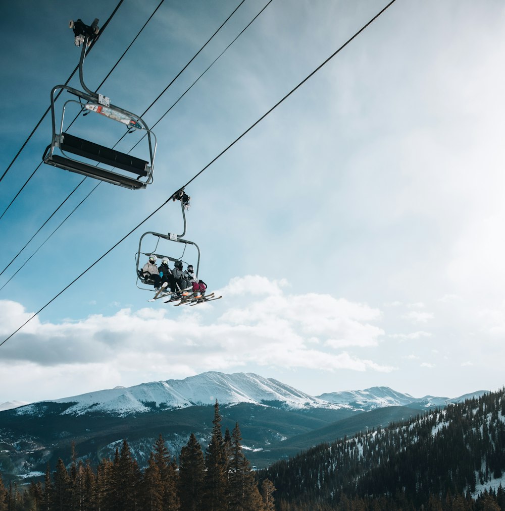 Persona que viaja en teleférico sobre una montaña cubierta de nieve durante el día