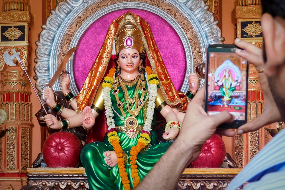 woman in red and gold sari dress holding gold and red trophy