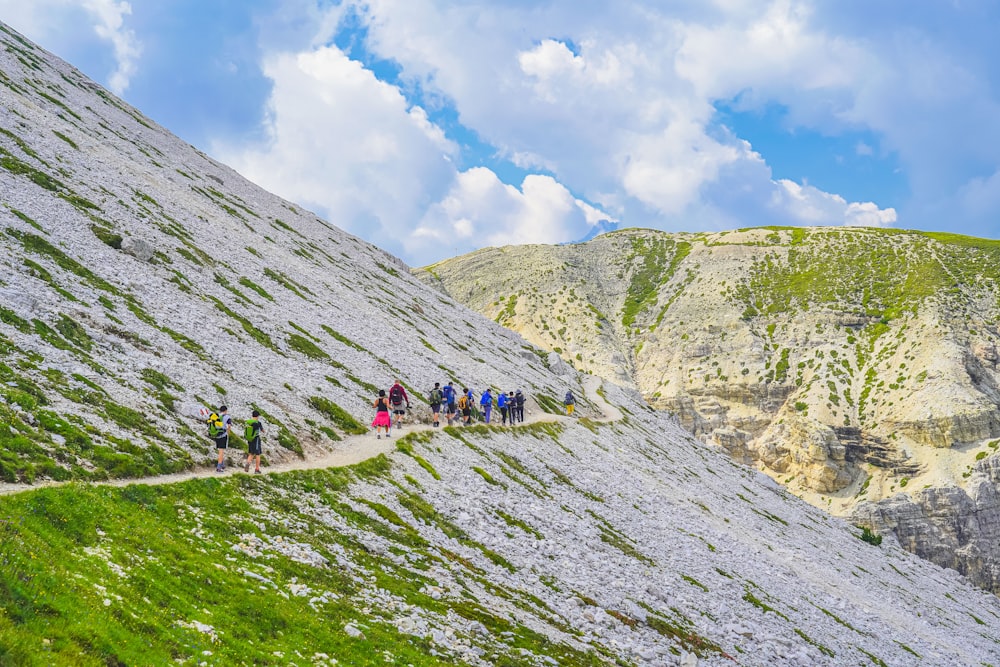 personnes faisant de la randonnée sur la montagne sous le ciel bleu pendant la journée