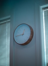 A minimalist wall clock hanging on a beige wall with subtle decorative elements around.