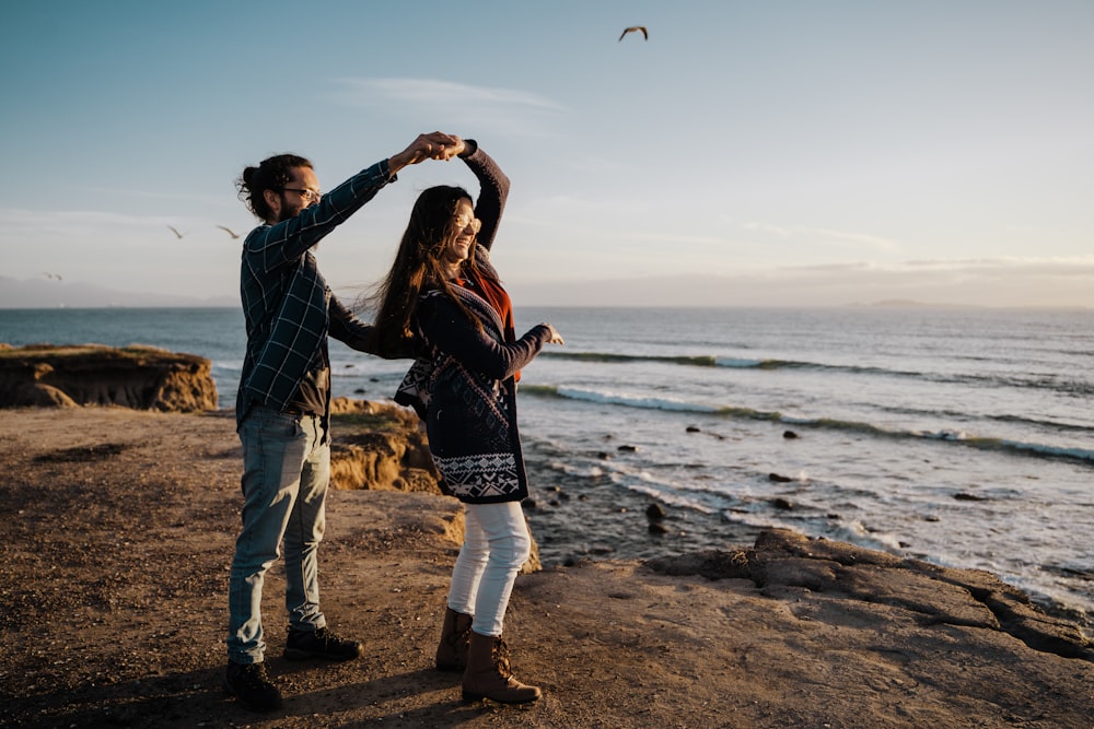 man and woman standing on beach during daytime