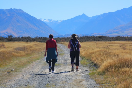2 women walking on dirt road during daytime