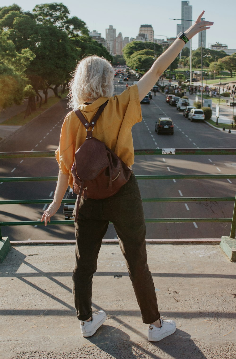 woman in brown jacket and brown pants standing on sidewalk during daytime