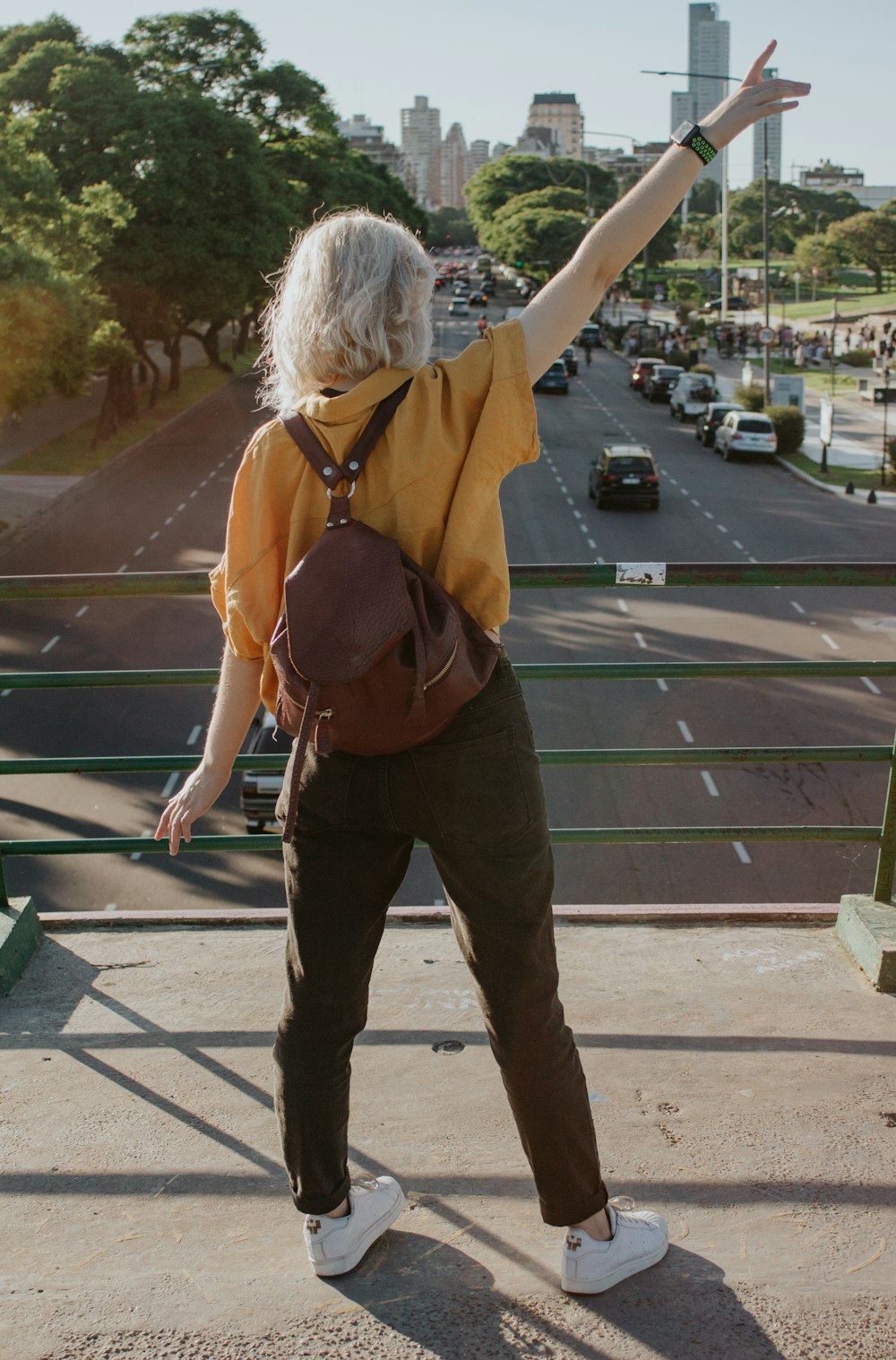 donna in giacca marrone e pantaloni marroni in piedi sul marciapiede durante il giorno