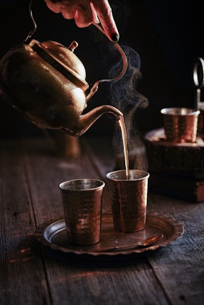stainless steel teapot pouring water on clear drinking glass