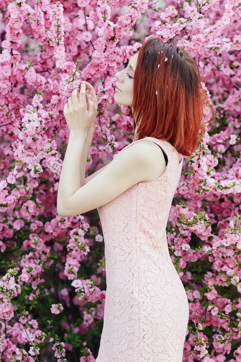 Frau in weißem ärmellosem Kleid steht tagsüber auf rosa Blumenfeld