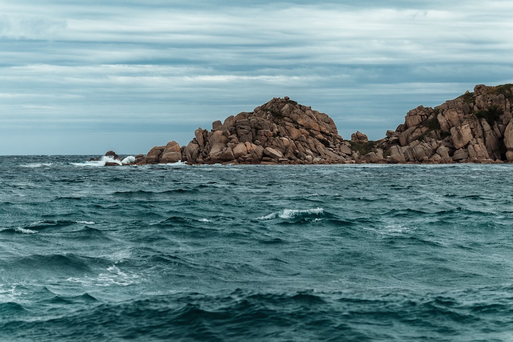 brown rock formation on sea under blue sky during daytime