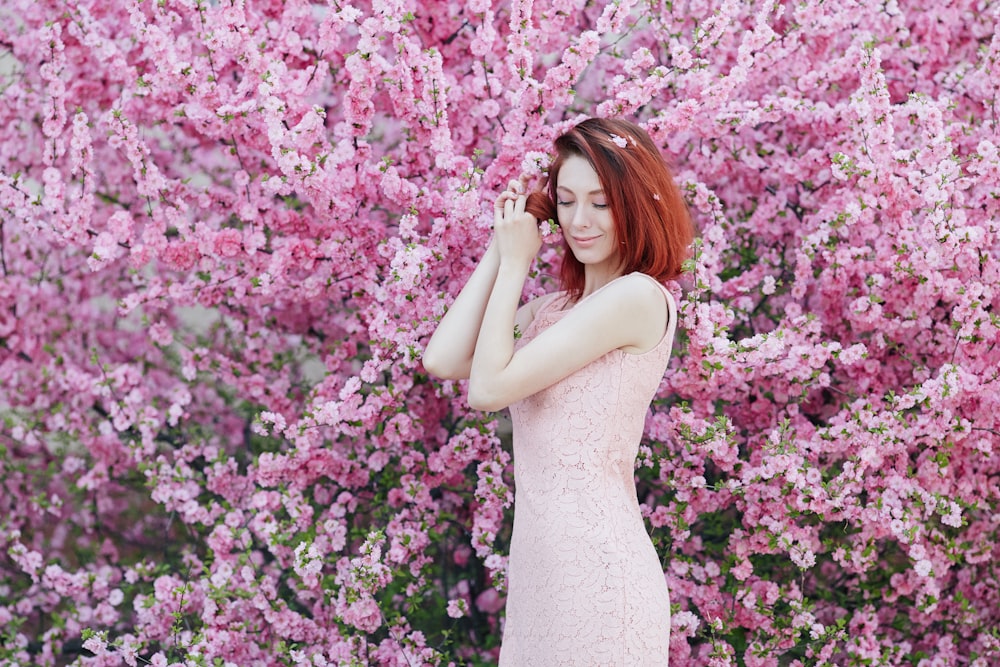 woman in white sleeveless dress standing beside pink flowers