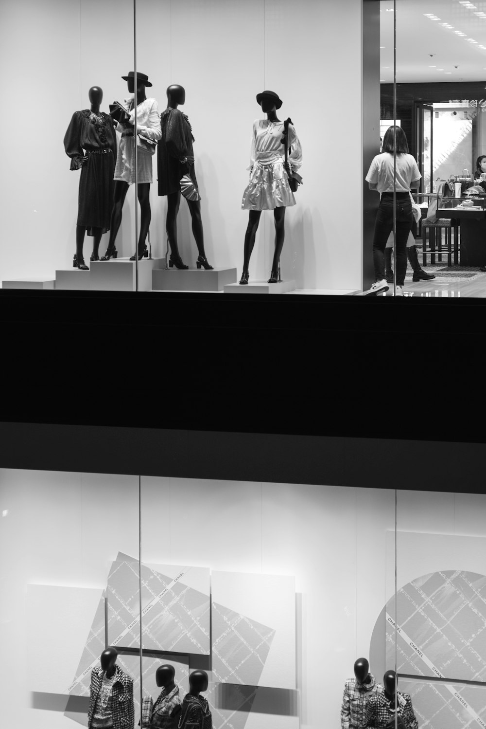 Foto en escala de grises de mujer con vestido negro de pie frente al espejo