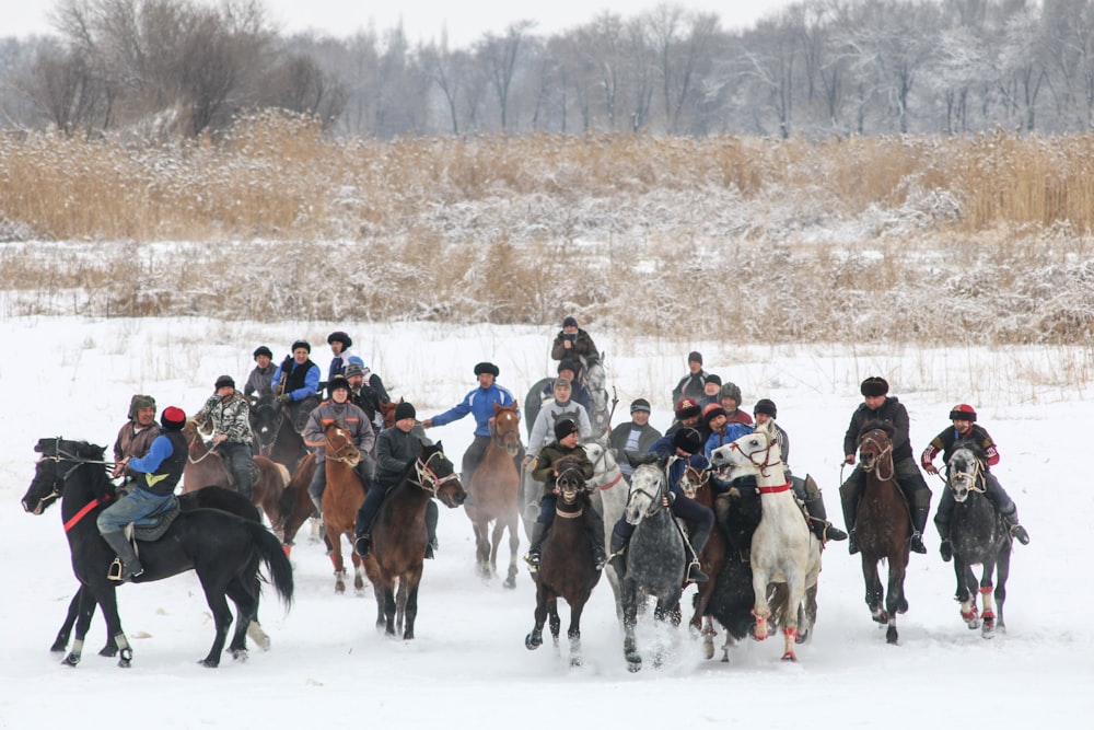 people riding horses on snow covered ground during daytime