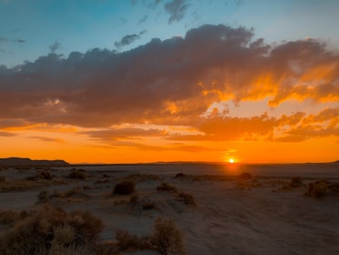 A wide desert landscape with dramatic clouds and warm tones.