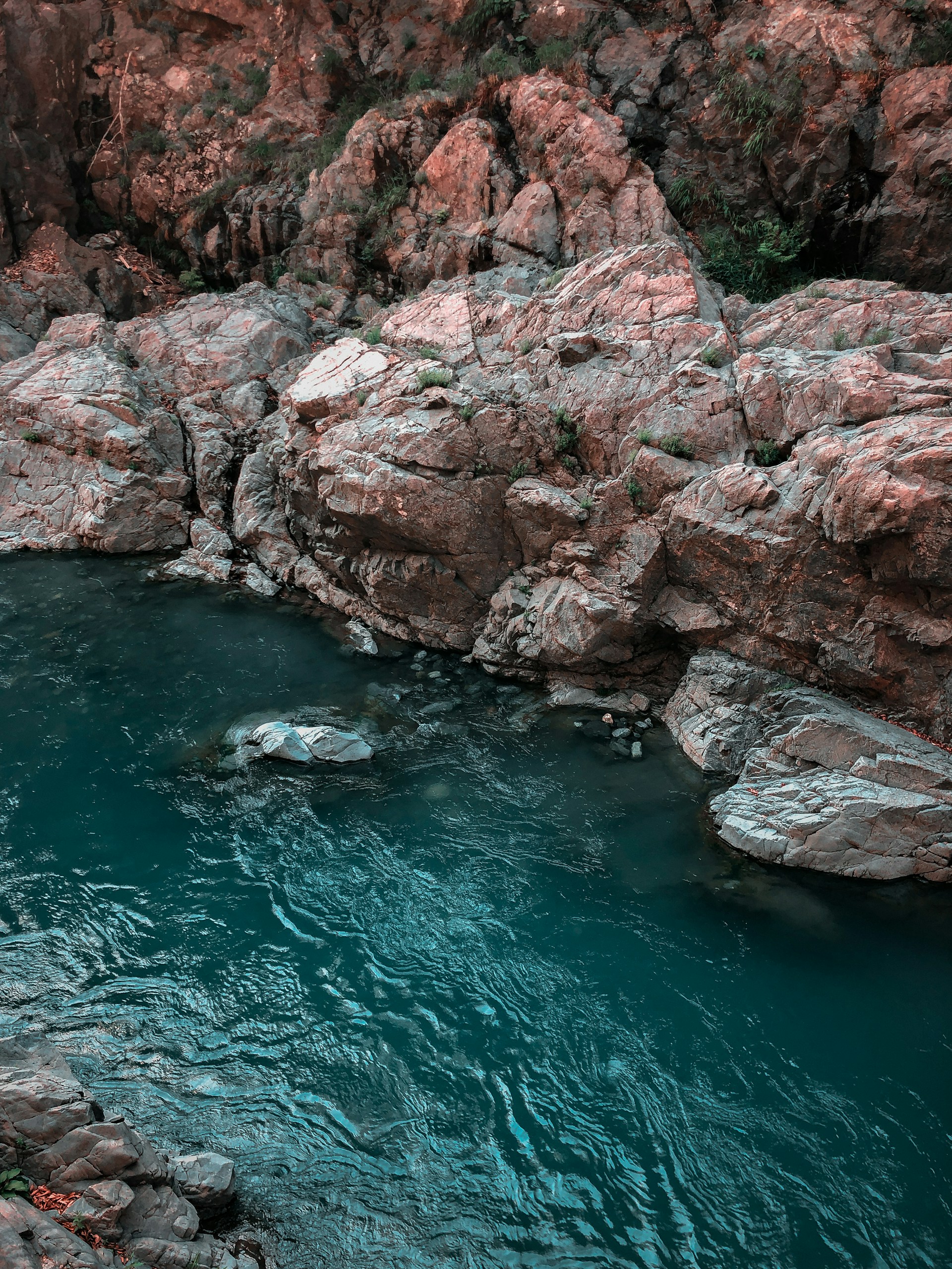 brown rocky mountain beside body of water during daytime