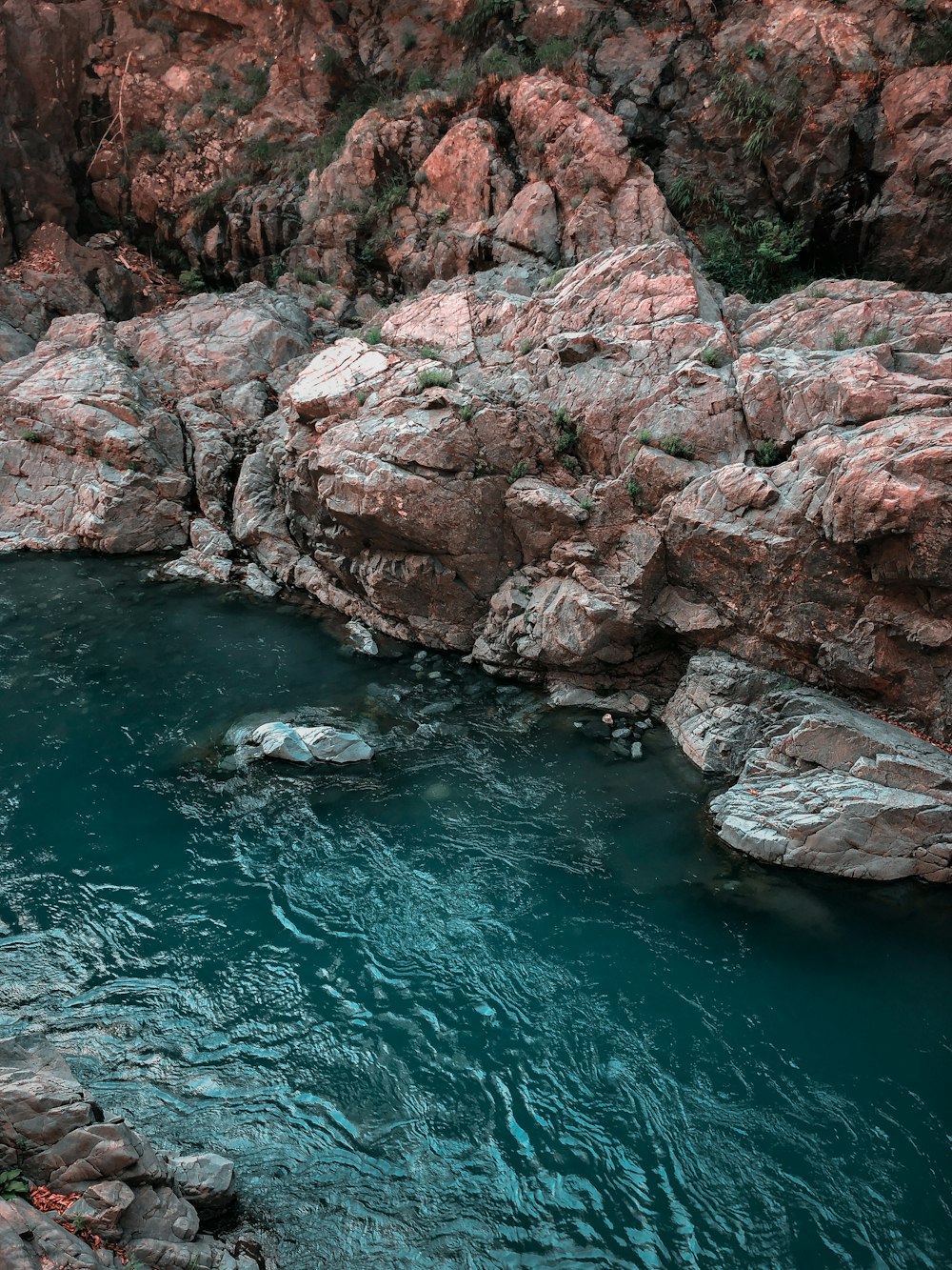 brown rocky mountain beside body of water during daytime