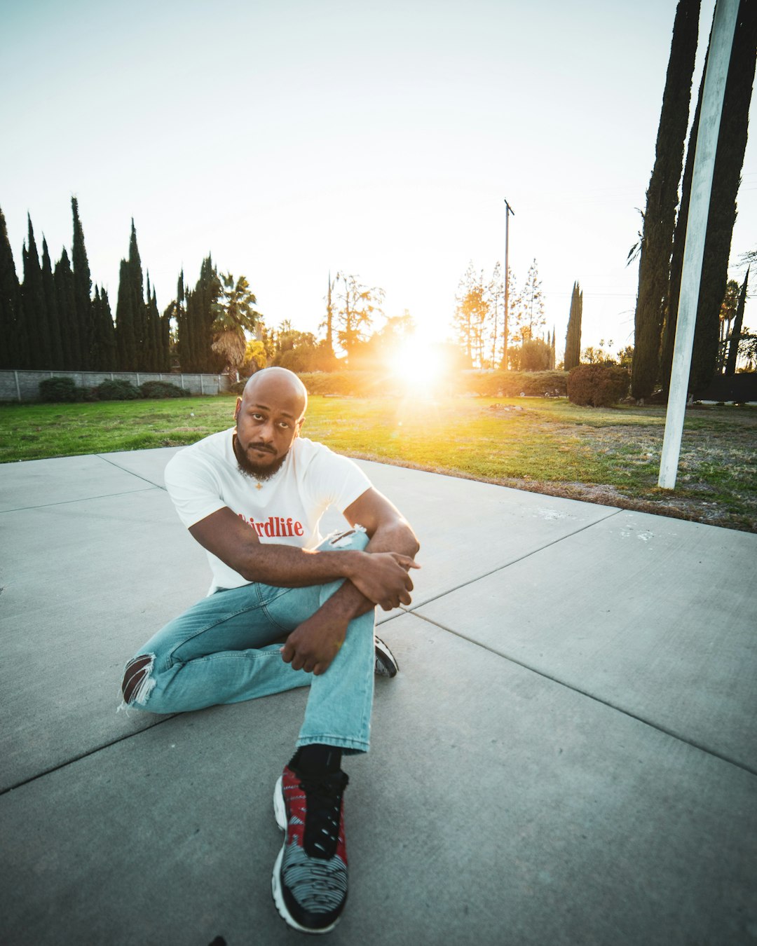 man in white crew neck t-shirt sitting on gray concrete floor during daytime