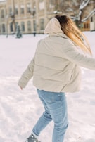 Man wearing a trendy puffer jacket walking through a snowy park.
