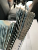 A large stack of banknotes bound together by a paper strip, set on a blurred background inside a vehicle.