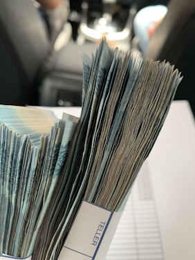 A large stack of banknotes bound together by a paper strip, set on a blurred background inside a vehicle.