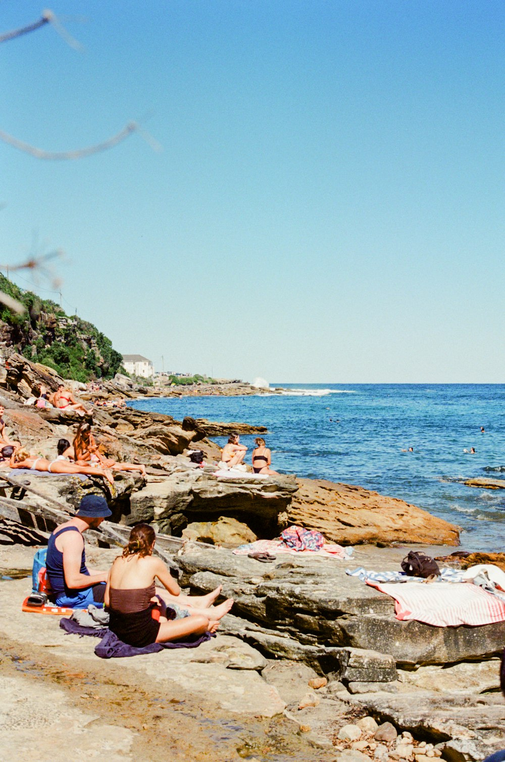 people sitting on rocks near sea during daytime