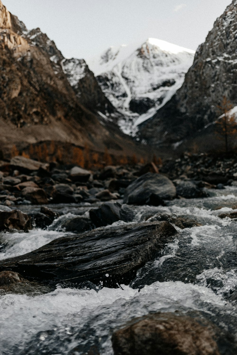 rocky river with snow covered mountain in distance