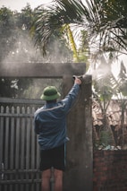 man in blue shirt and blue pants standing near green palm tree during daytime