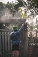 man in blue shirt and blue pants standing near green palm tree during daytime