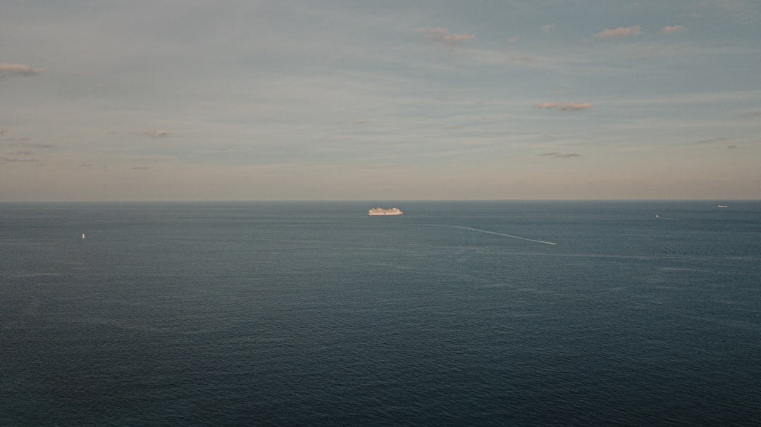 black boat on blue sea under white clouds during daytime