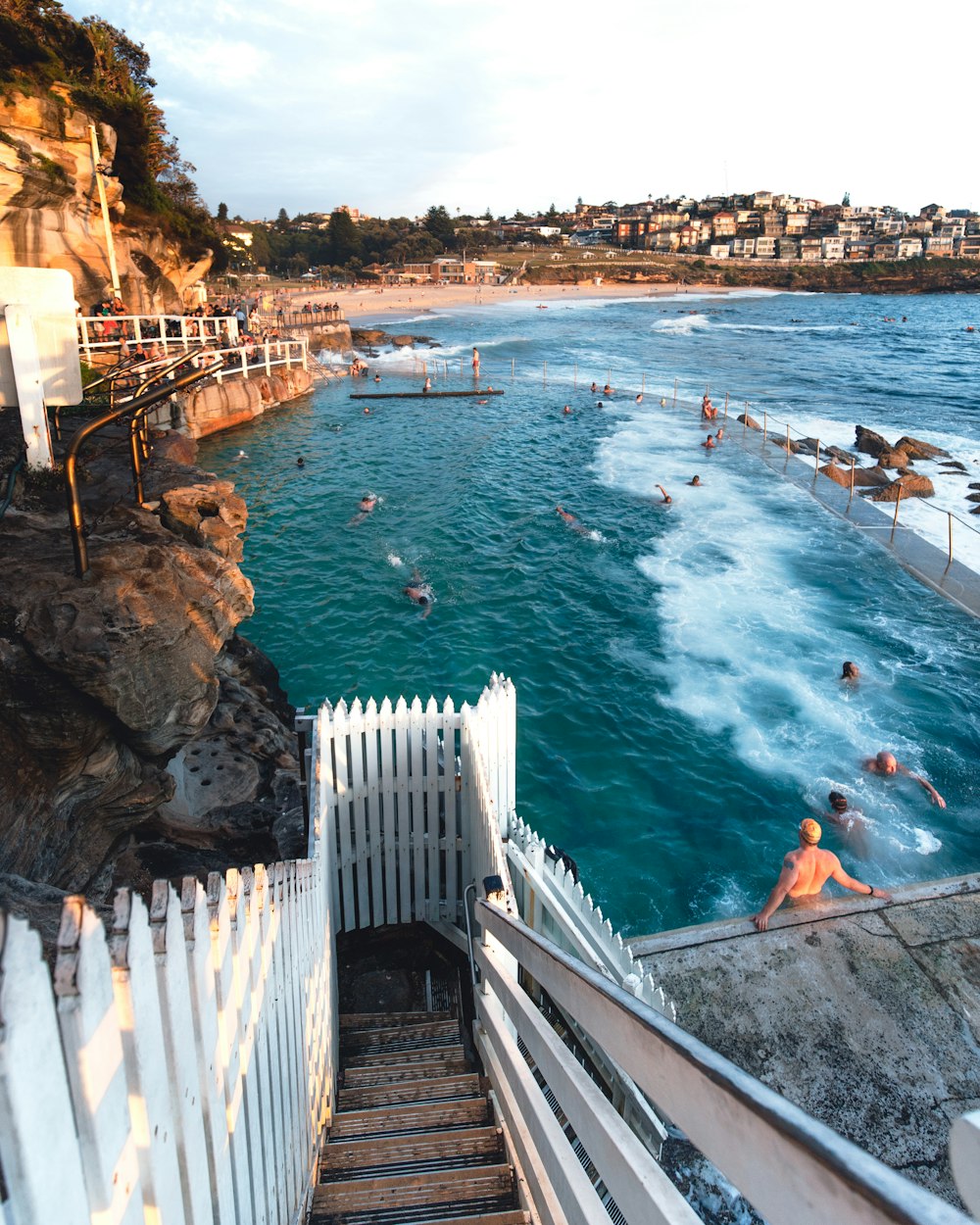 people walking on gray concrete bridge over blue sea during daytime