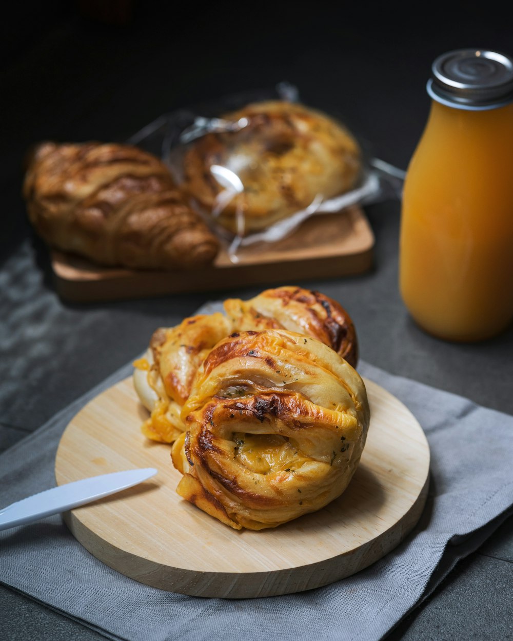 a wooden plate topped with onion rings next to a bottle of orange juice