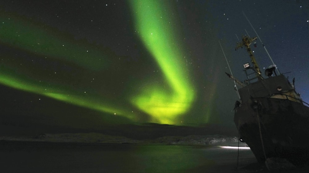 person standing on rock under green sky during night time