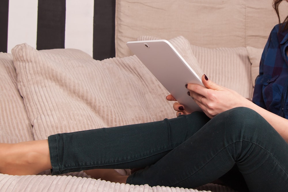 person in white shirt and black pants holding white ipad