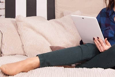person in black pants lying on bed using silver macbook comfortable zoom background