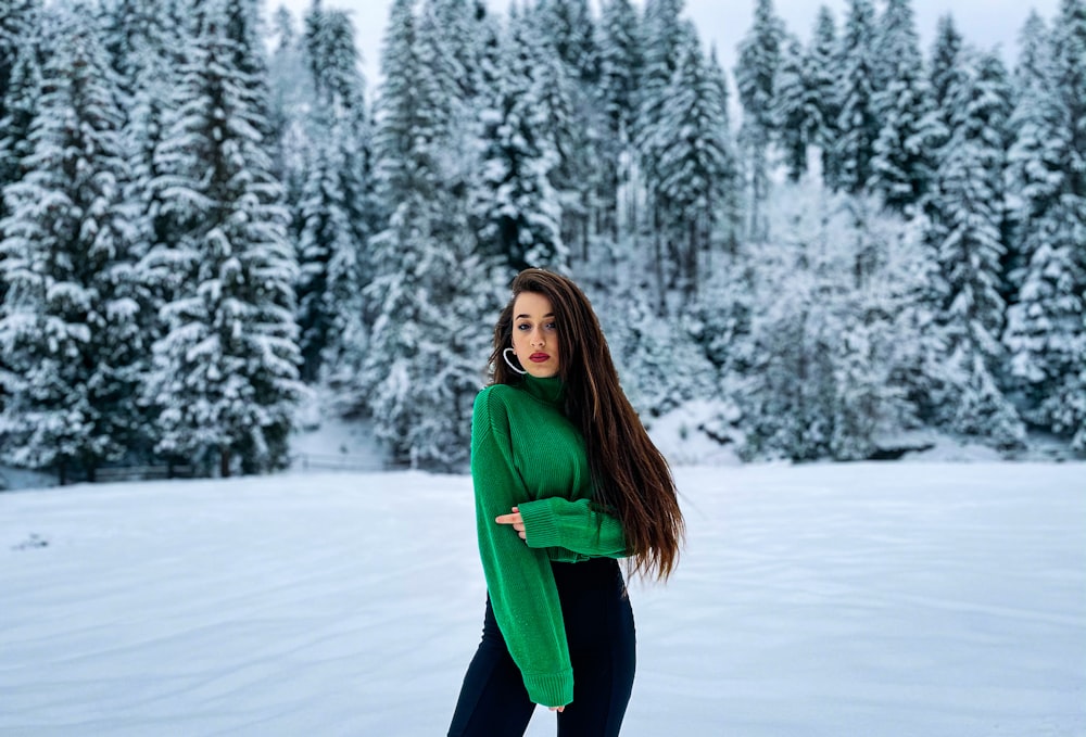 woman in green jacket and blue pants standing on snow covered ground during daytime