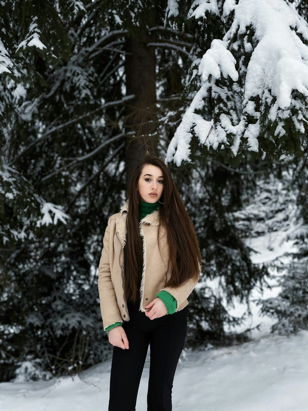 woman in brown jacket standing on snow covered ground