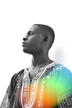 A person is shown in profile, wearing a patterned traditional garment with intricate designs. There are abstract color elements overlaying parts of the image, focusing on the garment.