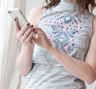 woman in gray and red tank top holding white smartphone