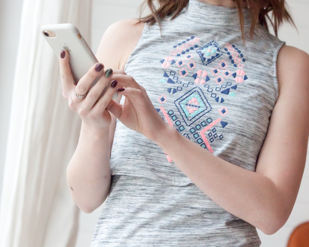 woman in gray and red tank top holding white smartphone