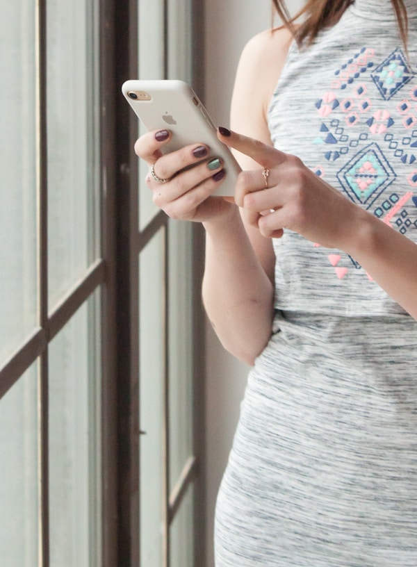 woman in gray tank top holding white smartphone