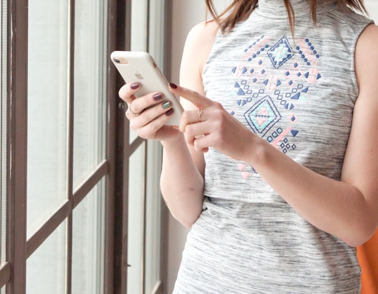 woman in gray and blue tank top holding white smartphone