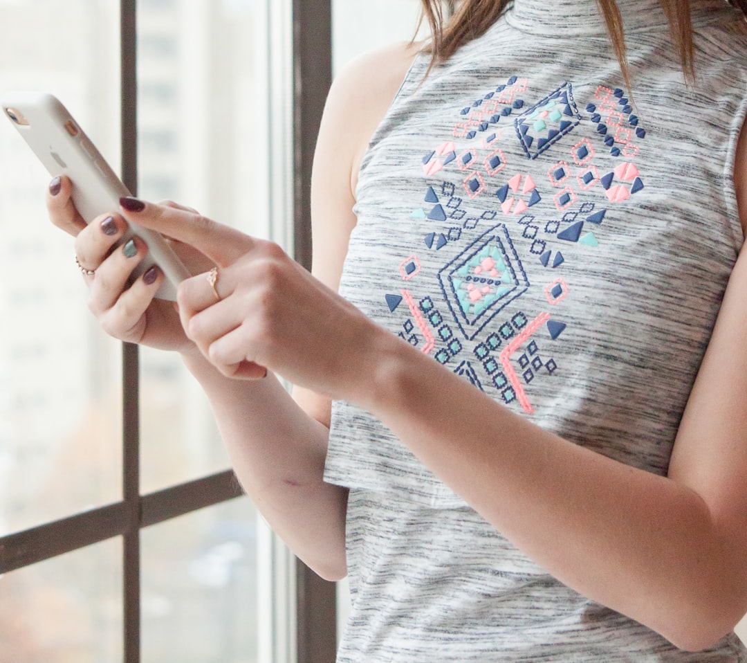 woman in blue tank top holding smartphone