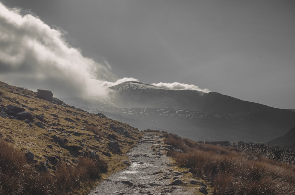 brown grass field near mountain under white clouds during daytime