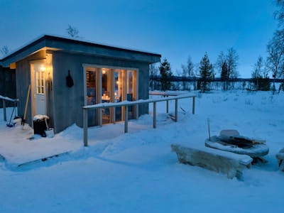 Warm glow from the cabin’s fireplace visible through large windows at twilight.