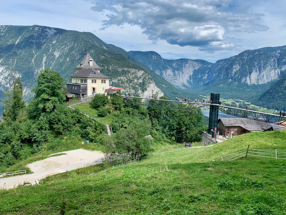 Weißes Betongebäude in der Nähe von grünen Bäumen und Bergen unter weißen Wolken tagsüber