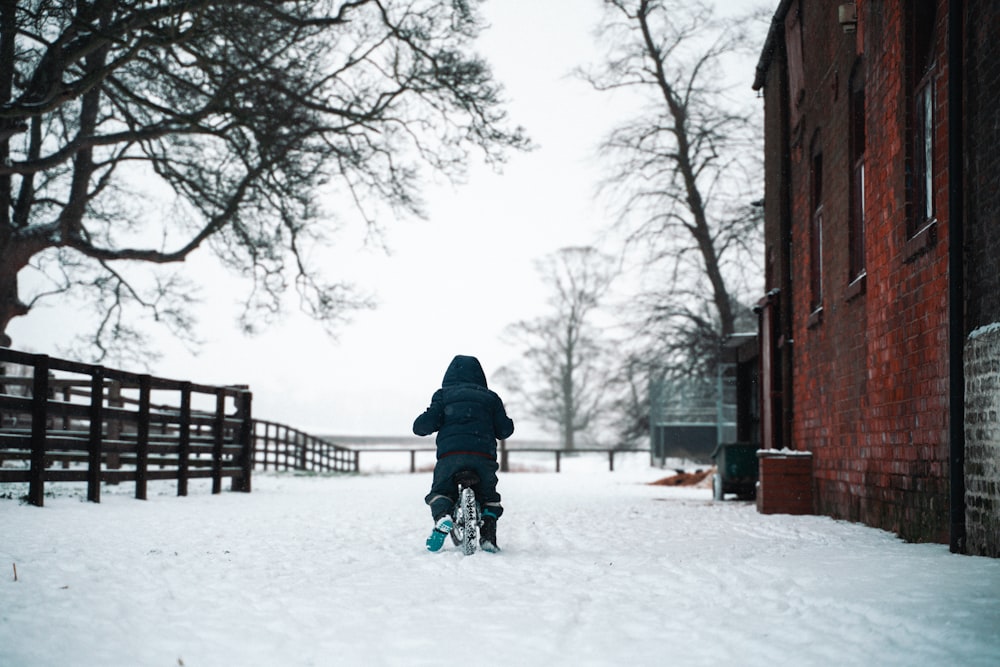 person in black jacket and blue pants walking on snow covered ground during daytime