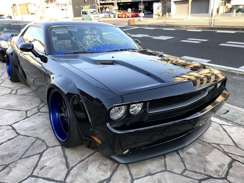 A sleek car with custom rims and tinted windows parked outdoors.